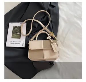 Détail du sac bandoulière bicolore beige et kaki avec étiquette logo et sangle
