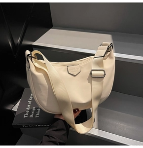 Detail of off-white nylon crescent bag featuring an adjustable strap and brand logo