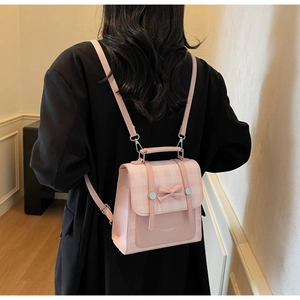 Detail of pink plaid mini backpack with decorative bow and straps worn by model