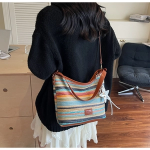 Detalle de bolso saco tejido de colores con correa de cuero y colgante de estrella
