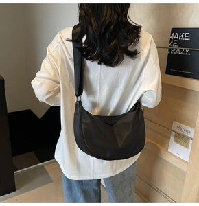 Close-up of black half-moon nylon crossbody bag with wide adjustable fabric shoulder strap