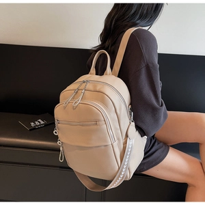 Detail of apricot lychee grain leather backpack with silver zippers and jacquard strap