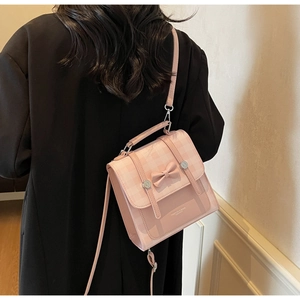 Detailed view of pink plaid crossbody bag with bow decoration shown on a model's back
