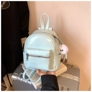 Detail of mint green mini PU leather backpack with silver zipper and fuzzy charm