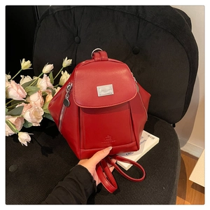 Detail of red leather backpack featuring silver hardware and side zipper accents