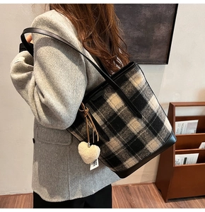 Détail du sac seau en laine à carreaux avec bordure en cuir et breloque coeur