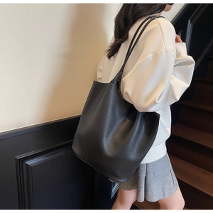 Detailed texture of black litchi pattern leather tote bag shown in a lifestyle setting