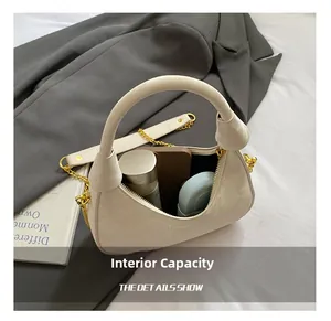 Détail de l'intérieur d'un sac demi-lune blanc cassé contenant des objets du quotidien
