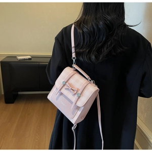 Detailed view of a pink plaid mini backpack featuring a decorative 3D bow and logo