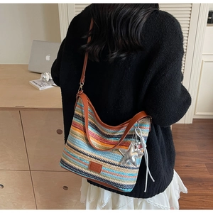 Detalle de bolso tejido a rayas de colores con correa de cuero marrón y colgante de estrella