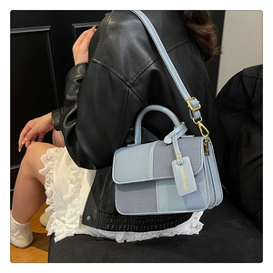 Détail du sac à main bleu clair avec ferrures dorées et étiquette de mode sur mannequin