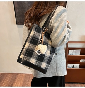Détails du sac seau en tweed à carreaux avec base en cuir noir et breloque coeur