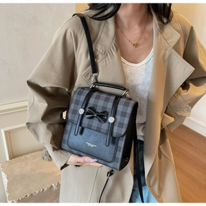 Detail of British grey plaid crossbody bag with a black bow and fashion leather logo
