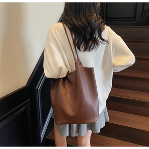 Deep brown pebble leather tote bag shown on model for size and scale perspective