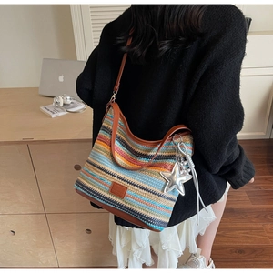 Detalle del bolso hobo de punto multicolor con colgante de estrella y correa de cuero marrón