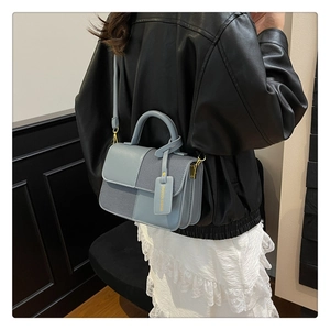 Détail du sac bandoulière bicolore en cuir bleu et tissu avec finitions métalliques dorées