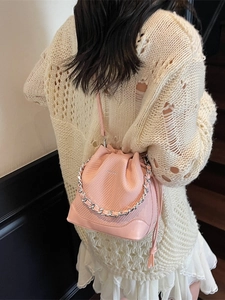 Fashionable pink drawstring bucket bag with chain handle styled with a beige knit outfit