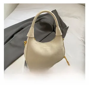 Détail du sac à main en daim crème avec chaîne dorée élégante et design arrondi chic