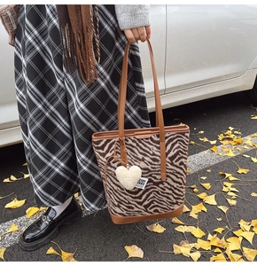 Détail du sac cabas en laine à motif zèbre avec breloque cœur et fine bandoulière en cuir