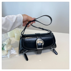 Detail of black leather bag featuring silver horseshoe buckle and metallic zip accents