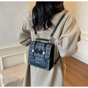 Detail of checkered backpack with black bow and fashion leather text on beige coat