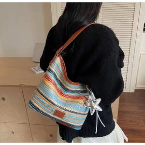 Detalle del bolso de cubo tejido bohemio con ribete de cuero y dije de estrella