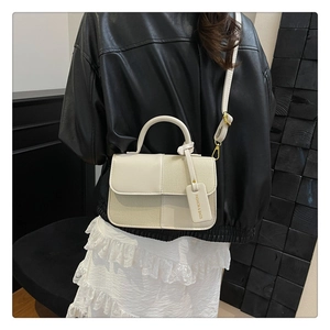 Détail du sac bandoulière crème avec mélange de matières et étiquette mode sur mannequin