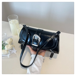 Detail of glossy black shoulder bag featuring a prominent silver buckle and metallic zipper