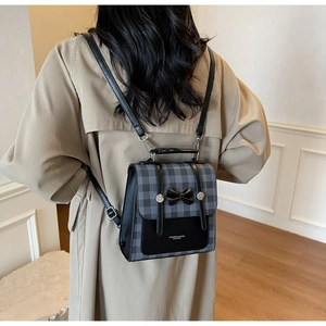 Detail of British style checkered backpack with bow accent worn on a trench coat
