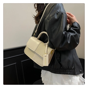 Gros plan d'un sac bandoulière en similicuir crème avec surpiqûres géométriques chic