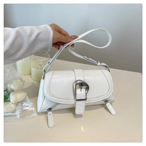 Macro detail of white leather shoulder bag featuring large silver metal buckle and zip accents