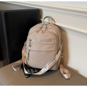 Detail view of beige pebbled leather backpack with metal chains and woven straps