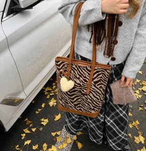 Detailaufnahme der Zebra-Felloptik Tasche mit Ledergriffen und Herz-Anhänger