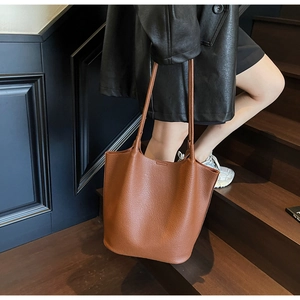 Close-up of brown litchi pattern leather tote bag carried on a wooden staircase