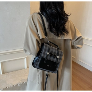 Detail shot of the vintage plaid backpack with black leather bow and silver buckles on model