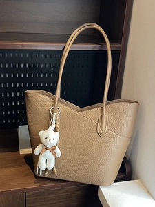 Braune Leder-Shopper-Tasche mit Kieselstruktur und Bärenanhänger im Regal