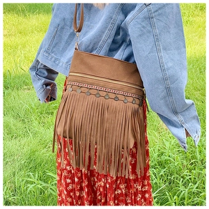 Detail of bohemian brown tassel shoulder bag with ethnic embroidery on floral dress