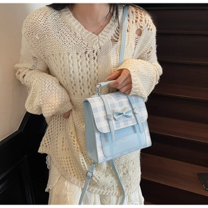 Detail of light blue plaid backpack with a decorative 3D bow and adjustable strap