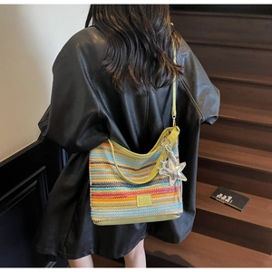 Detalle del bolso de hombro tejido a rayas coloridas con correas verdes y dije de estrella