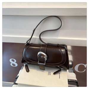 Detail view of a vintage dark brown patent leather shoulder bag with silver horseshoe buckle
