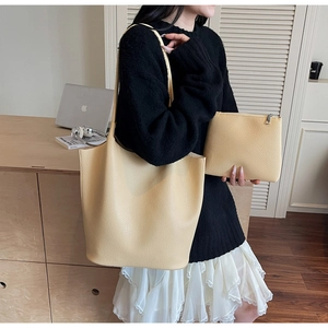 Chic cream beige leather tote bag with matching zippered pouch shown in a modern interior