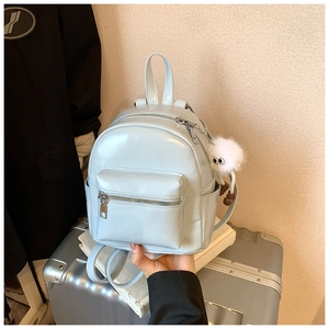 Detailed close-up of light blue glossy mini backpack with a white plush doll charm