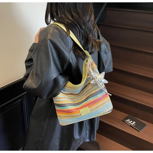 Detalle de un bolso tipo cubo tejido a rayas coloridas con colgante de estrella de plata