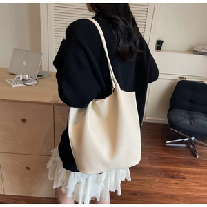 Minimalist creamy white tote bag with lychee texture shown worn over the shoulder