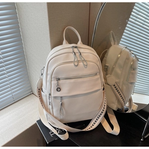 Detail showing cream lychee grain leather backpack with silver zippers and woven strap
