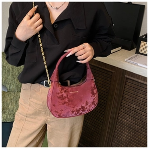 Détail du sac demi-lune en velours bordeaux avec chaîne dorée et lettrage du logo