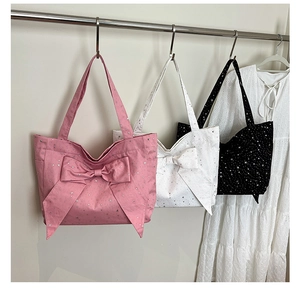 Detailed view of nylon tote bags in pink, black, and white with large bows and star prints