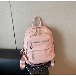 Detail of pink faux leather backpack featuring lychee texture and silver metal zippers