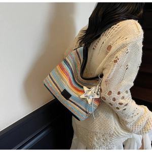 Detalle del bolso bandolera tejido de colores con colgante de estrella y correa de cuero