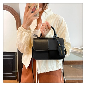 Détail du sac à bandoulière noir en patchwork avec boucle dorée et étiquette mode